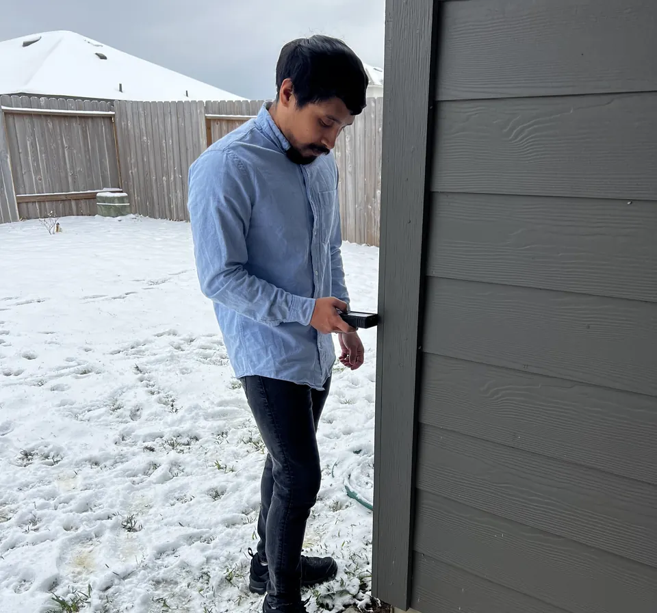 An RSDS appraiser and Marine Corps veteran measuring a home exterior in the snow